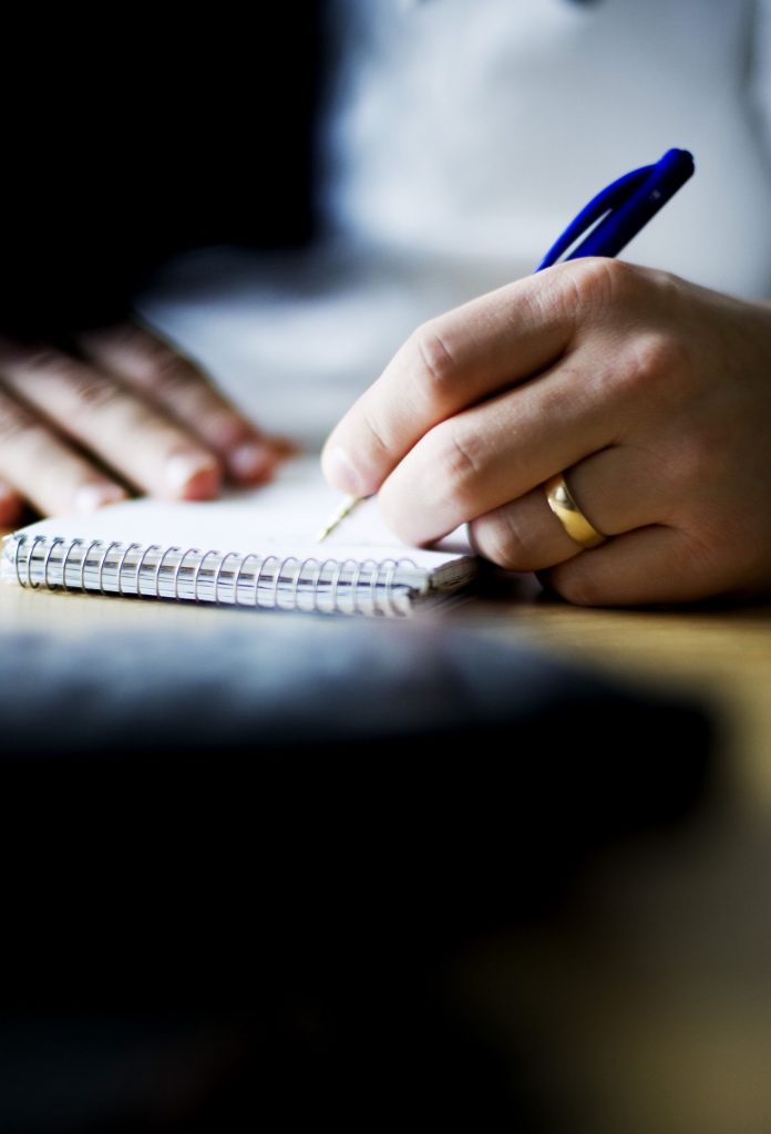 Hånd som skriver i notatblokk