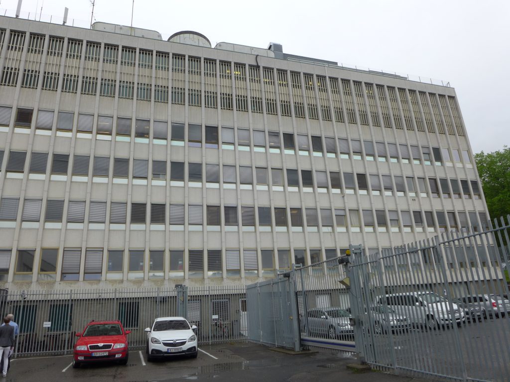 Stor grå bygning med biler foran