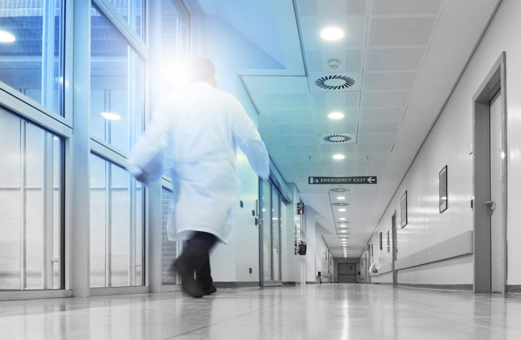 Person i hvit frakk går i sykehusgang