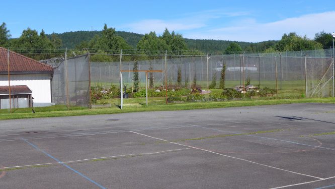 bilde av stor luftegård med asfalt og åpen dør til den nye hagen