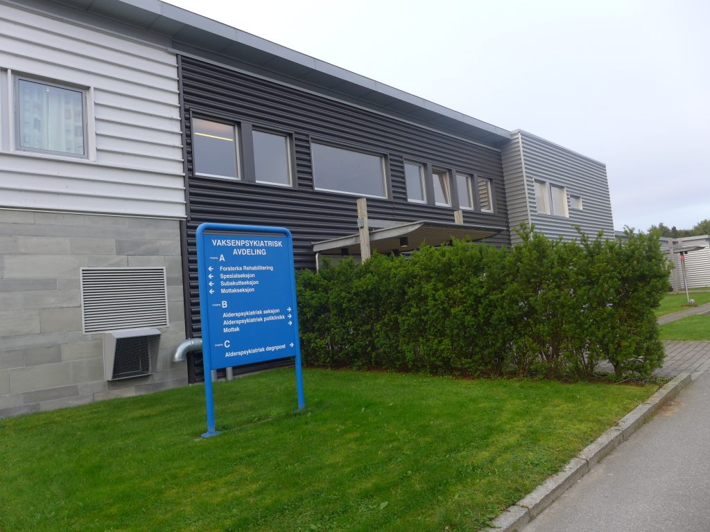 Blått skilt foran institusjonsbygg