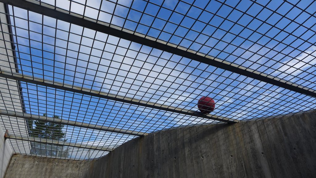 Gitter mot blå himmel med ball som ligger på gitteret