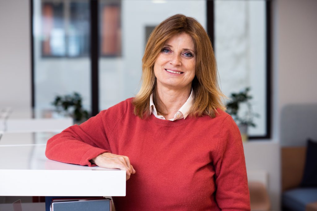 Sivilombud Hanne Harlem med rød genser med armen på bokhylle Foto: Mona Ødegård, Sivilombudet