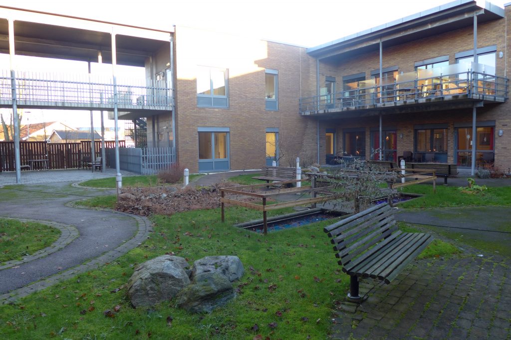 Sansehage ved sykehjem - planter, benk, bygning