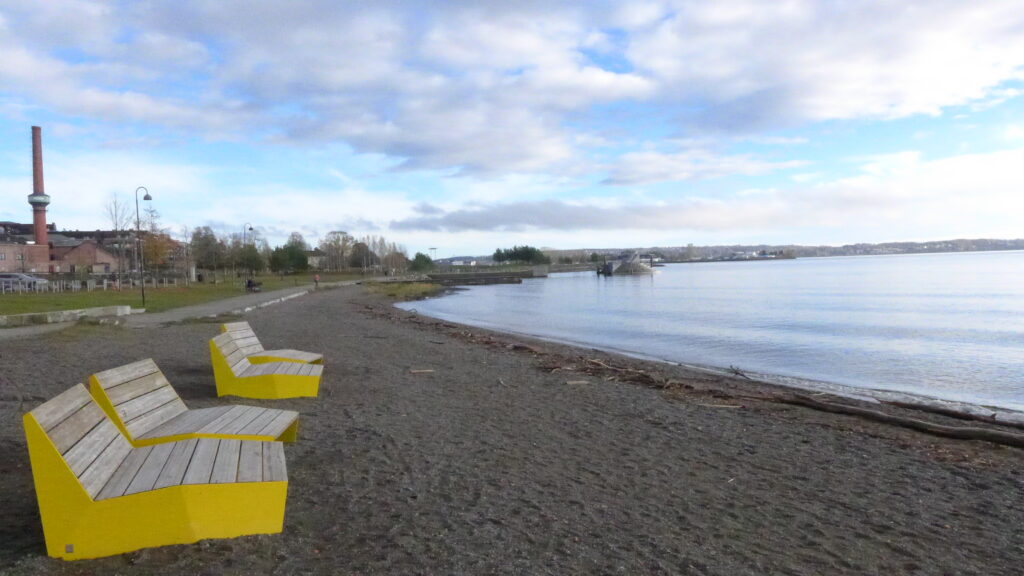 Utsikt over sjø med gule stoler i sanden