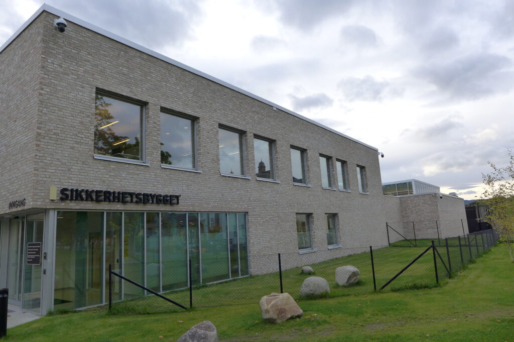 Grå bygning eksteriør, grønt gress og blå himmel