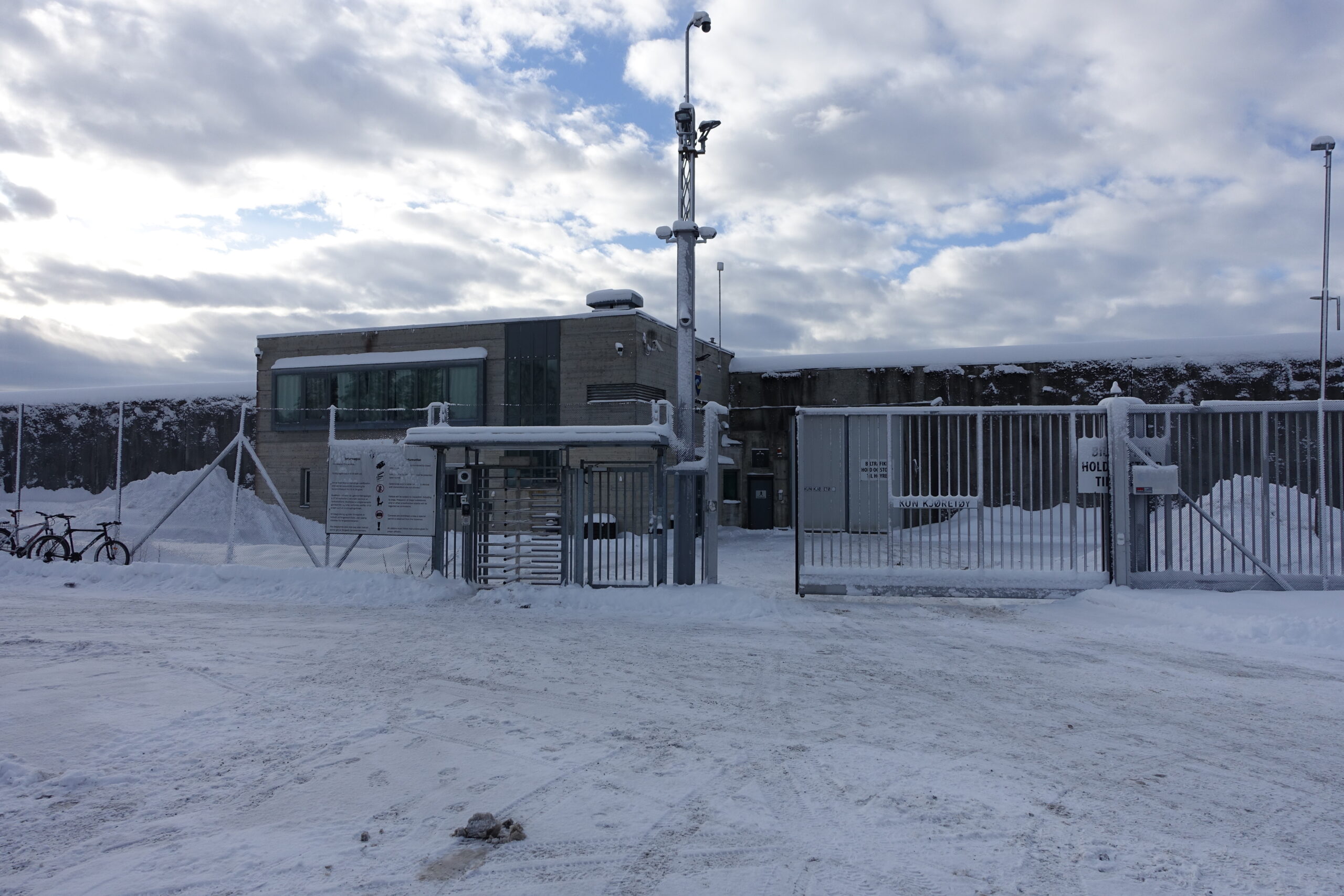 Gitter og grå bygning bak, snø foran.