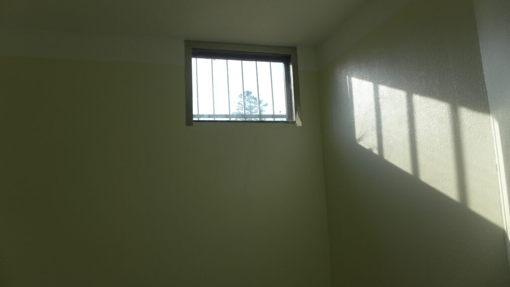 Lys faller inn fra vindu høyt oppe på fengselsvegg