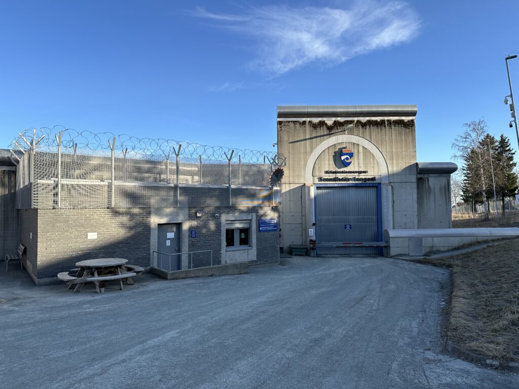 Grå bygning, inngangsparti fengsel med blå himmel over