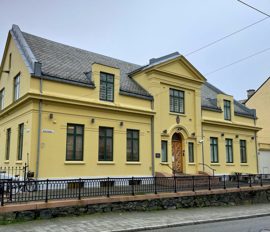 Gul bygning på gateplan med fortau og gate foran