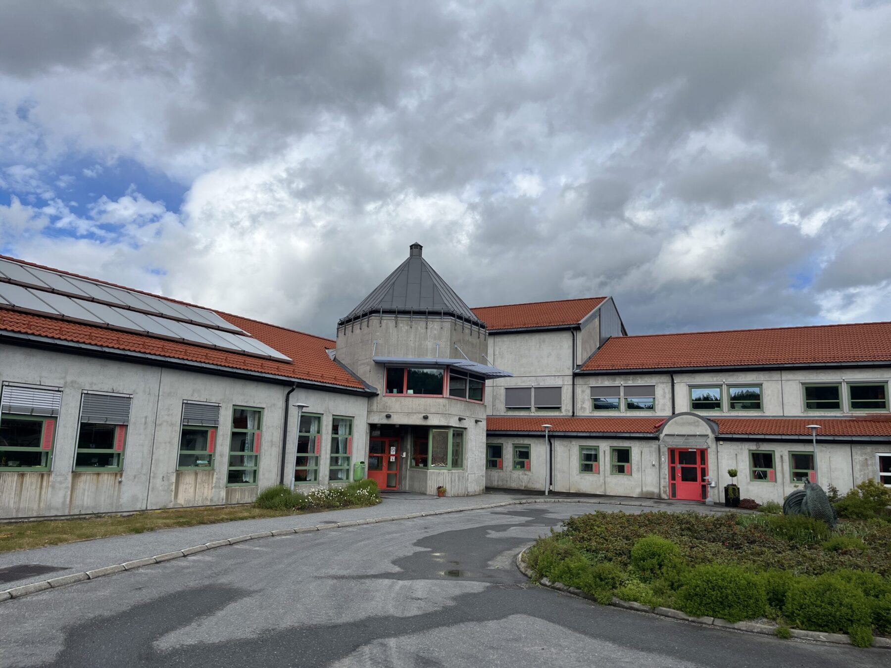 Eksteriørbilde av lys bygning med røde tak